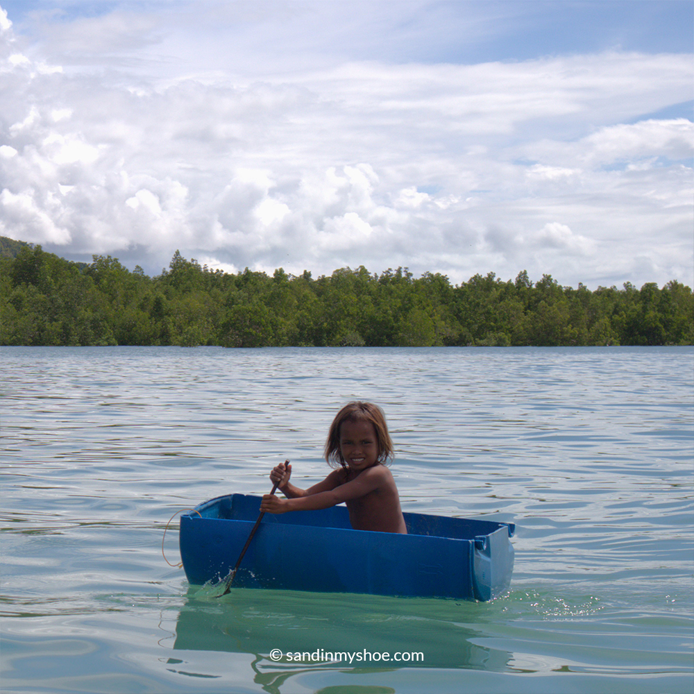 Young Sea Gypsy Malaysia girl floating on a handmade boat near her village
