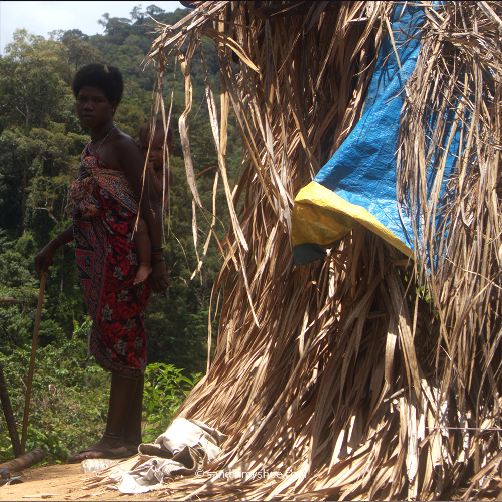Orang Asli tribe woman holding child in traditional village by Taman Negara rainforest