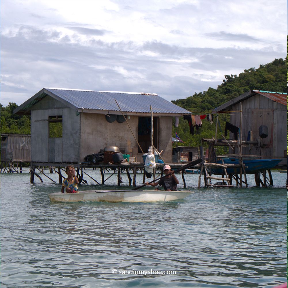 Two Bajau Laut boys rowing a small handmade boat off the Malaysian coast