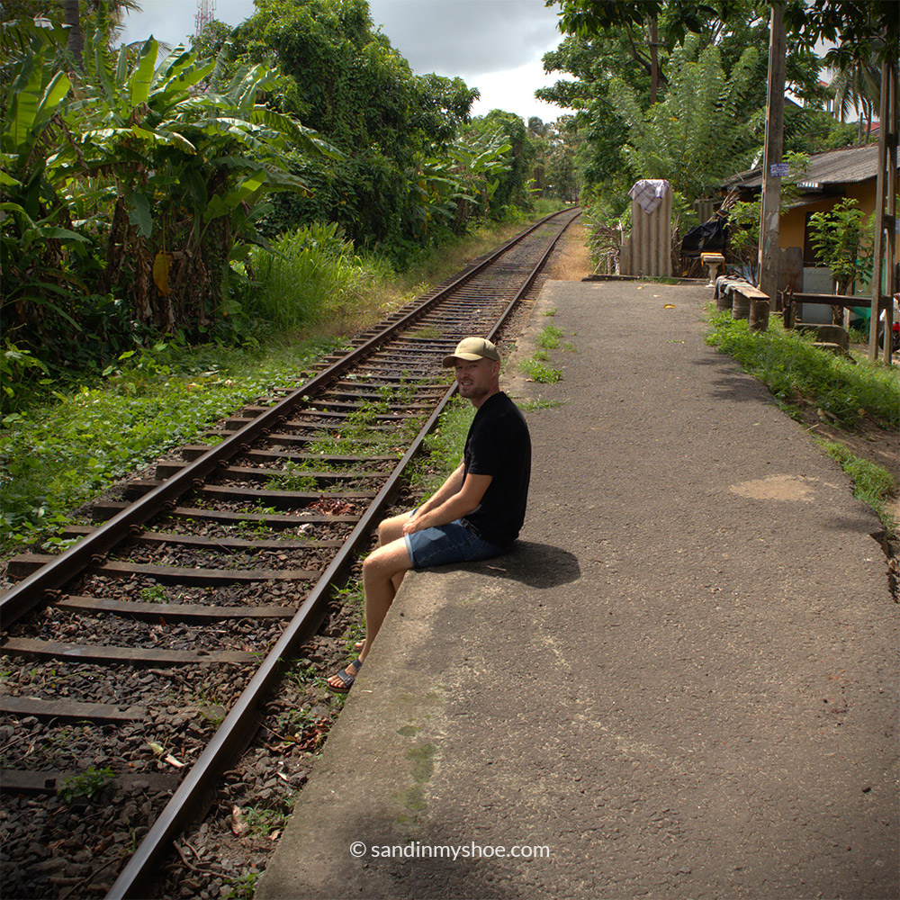 Petteri sitting next to railway tracks in Sri Lanka, pondering whether Colombo or Negombo is the best starting point during a Sri Lanka trip.