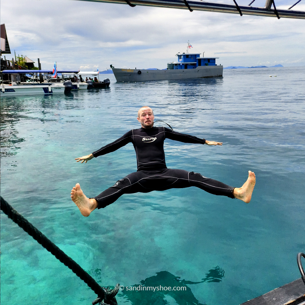 Petteri jumping back-first from a boat into crystal-clear waters in Semporna, Malaysia — one of the unforgettable Southeast Asia places to go for island adventures and snorkeling.