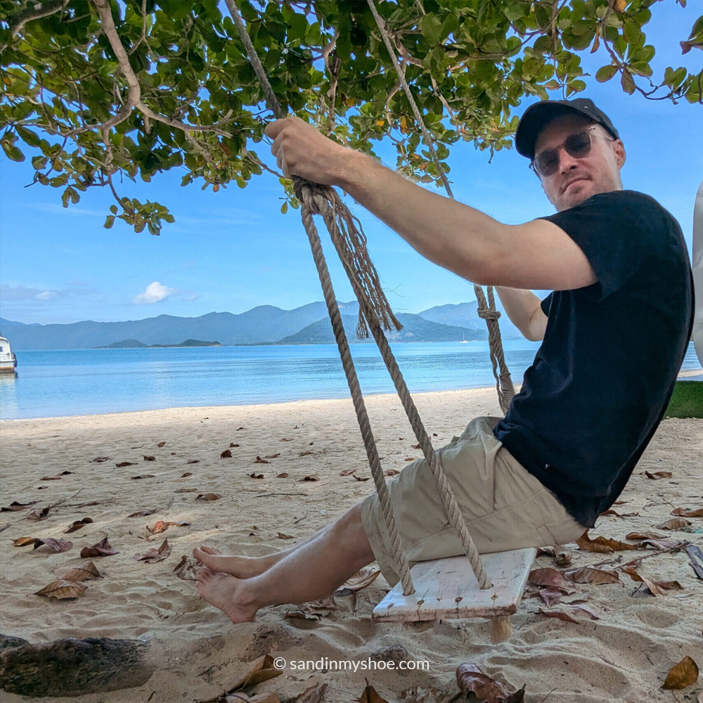 Petteri relaxing on a swing facing the serene beach in Vietnam, soaking in the coastal breeze and tropical vibes.