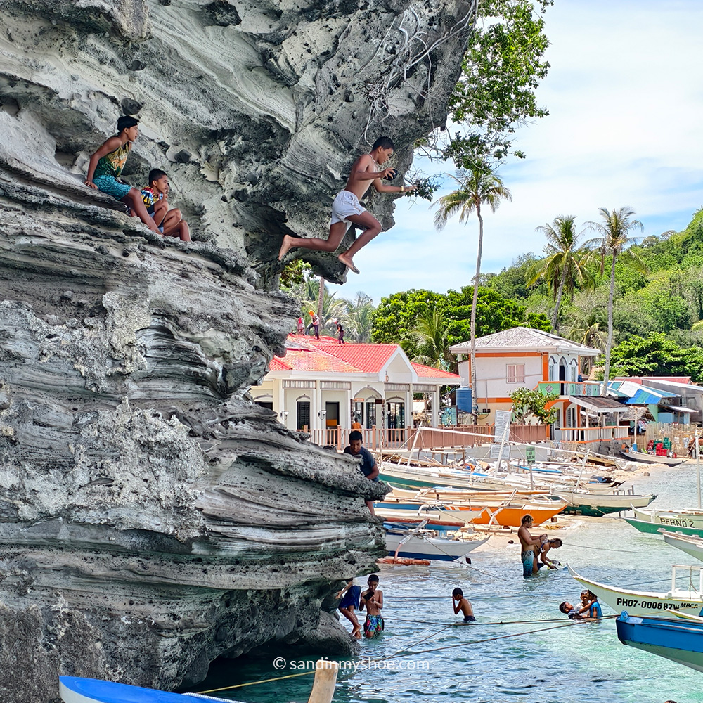 Children jumping into shallow water at the docks of Apo Island