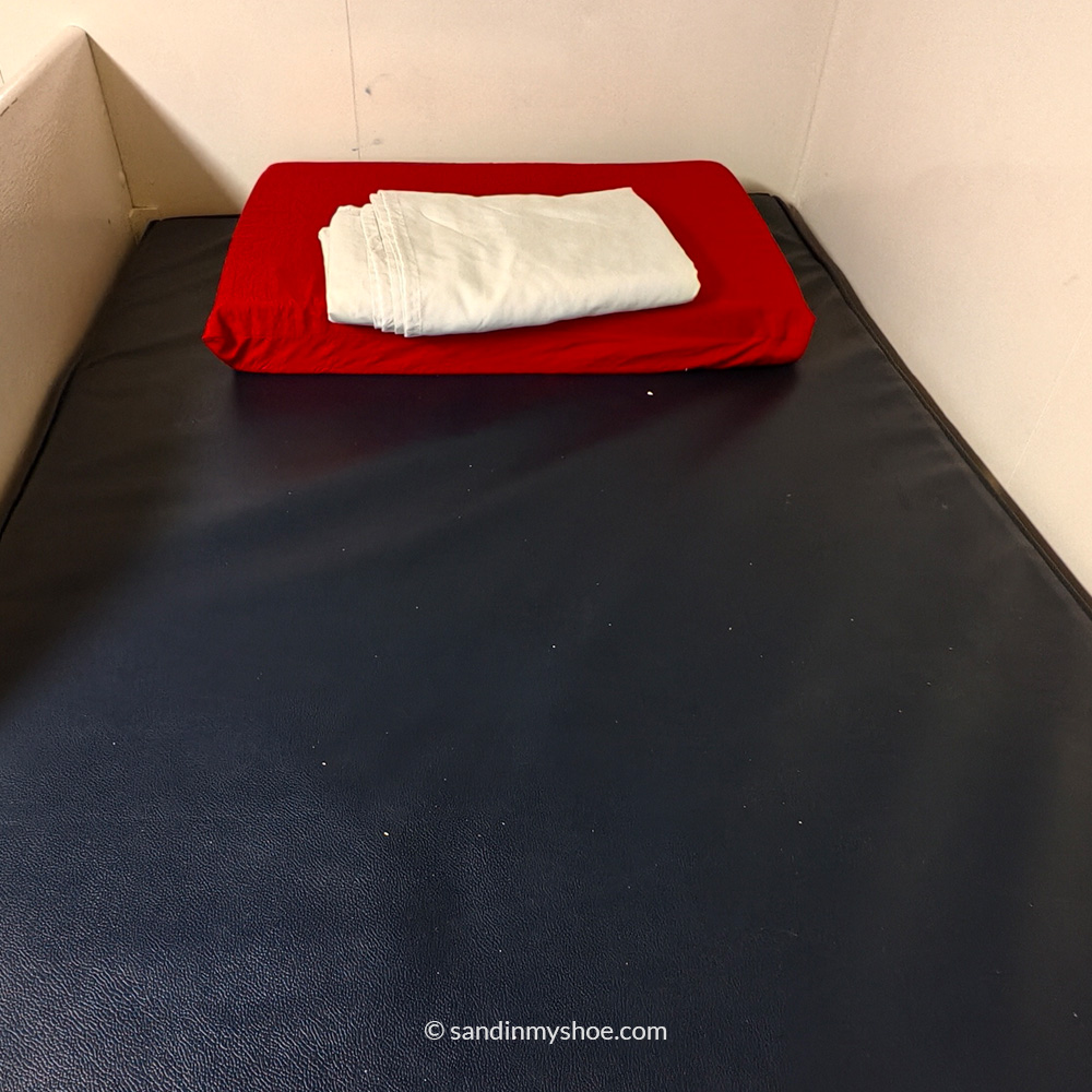 Business class bed with a plastic bottom and a very light blanket.