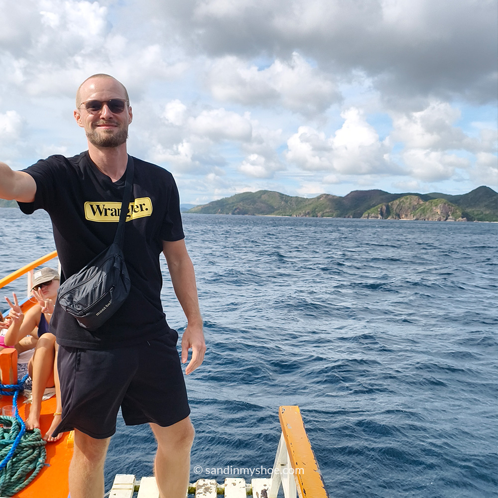Me posing on a bangka boat with blue waters in the background during the Coron–El Nido expedition.