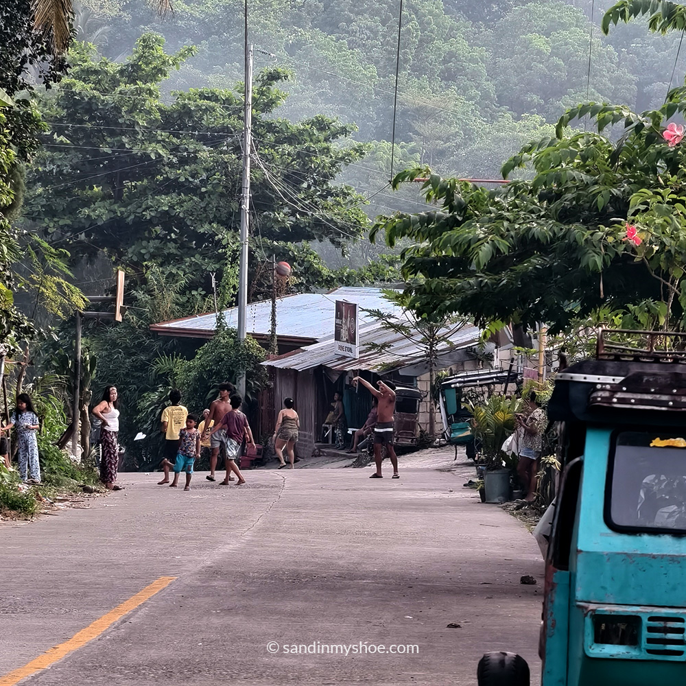 Children playing on a village street in the mountains of Cebu, surrounded by lush hills and rural scenery