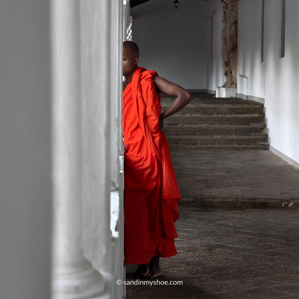A monk with orange robe talking on the phone