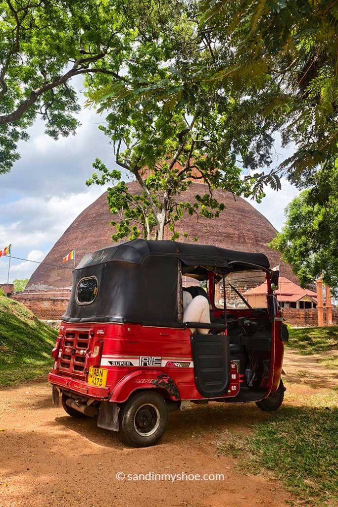 A tuk-tuk with a stupa behind it