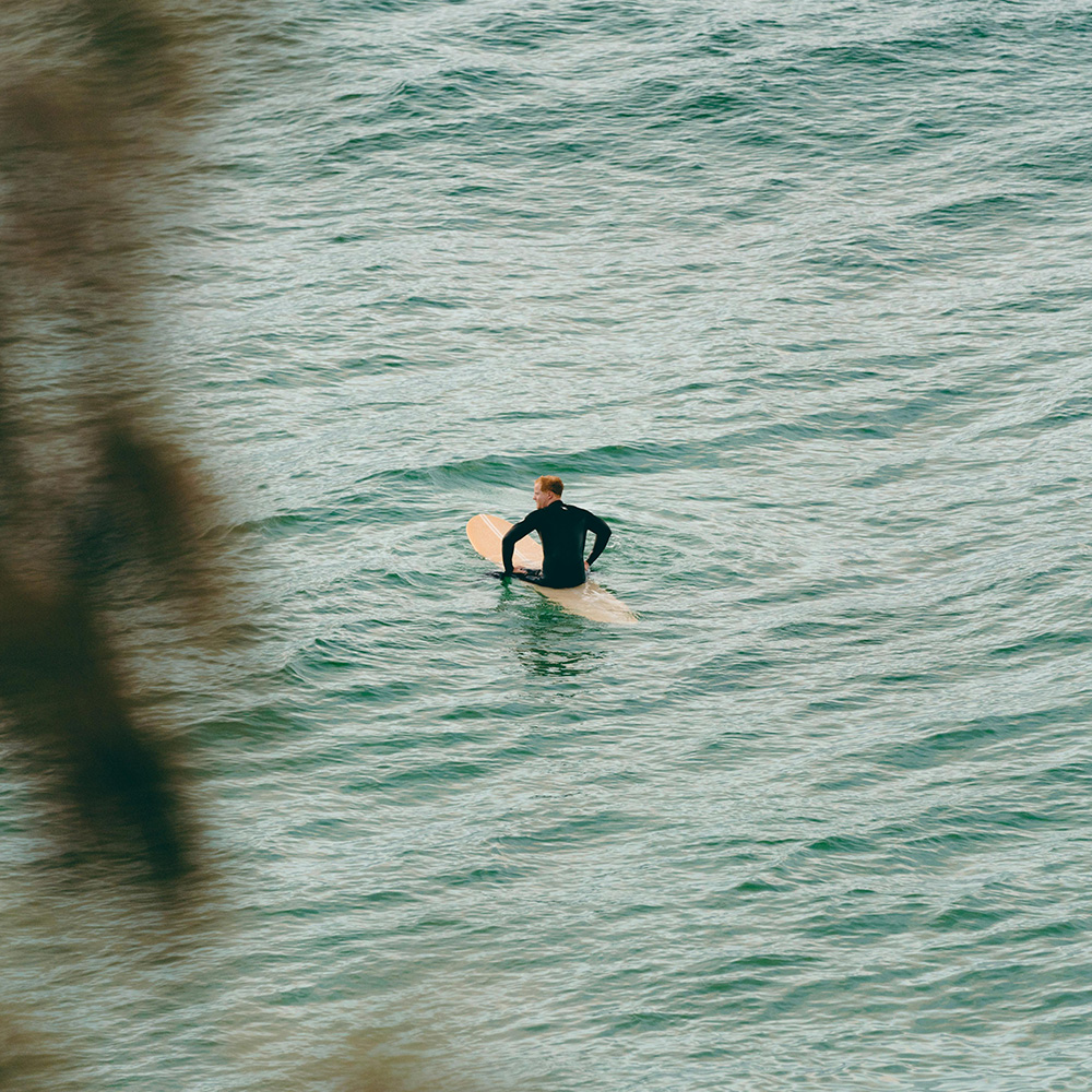 Surfer sitting on a surfboard in Arugam Bay, waiting for a wave during September, showing the calm east‑coast conditions travellers consider when asking if September is a good month to visit Sri Lanka.