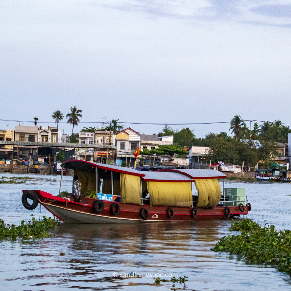 A lone wooden boat drifting along the Hau River, Can Tho