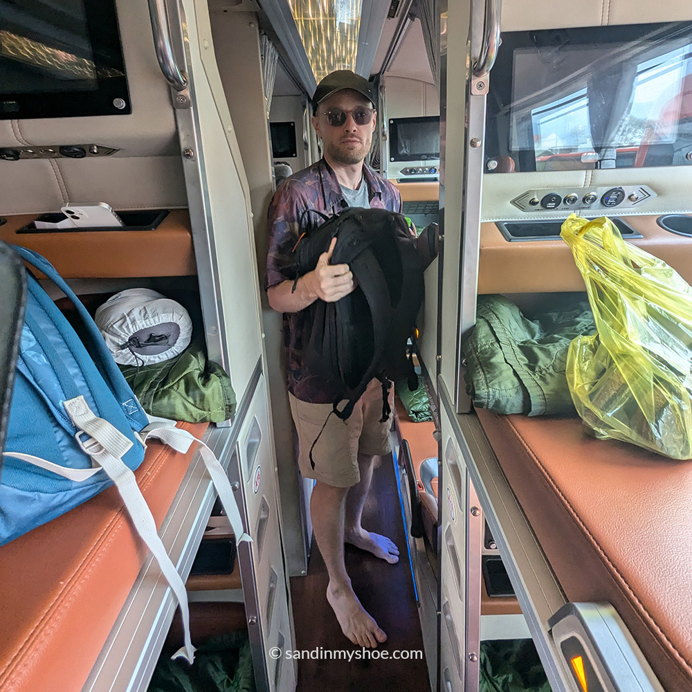 Petteri standing in the narrow hallway of a lying bus, with low ceilings and limited walking space.