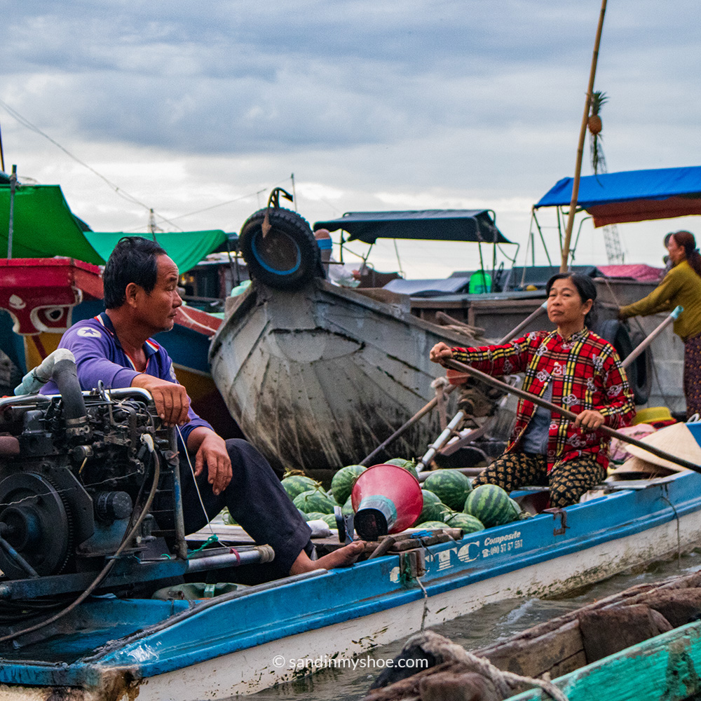 Two vendors on a boat in Cai Rang floating market in Can Tho, Mekong Delta