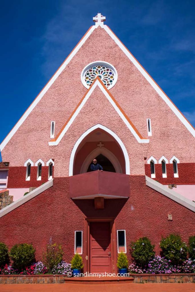 Domaine de Marie Church’s pink exterior overlooking the courtyard, with a visitor stading in front of the main entrance