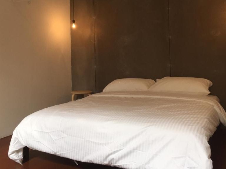 Minimal private room at The Frame Guesthouse with a simple bed and bare‑bones furnishings.