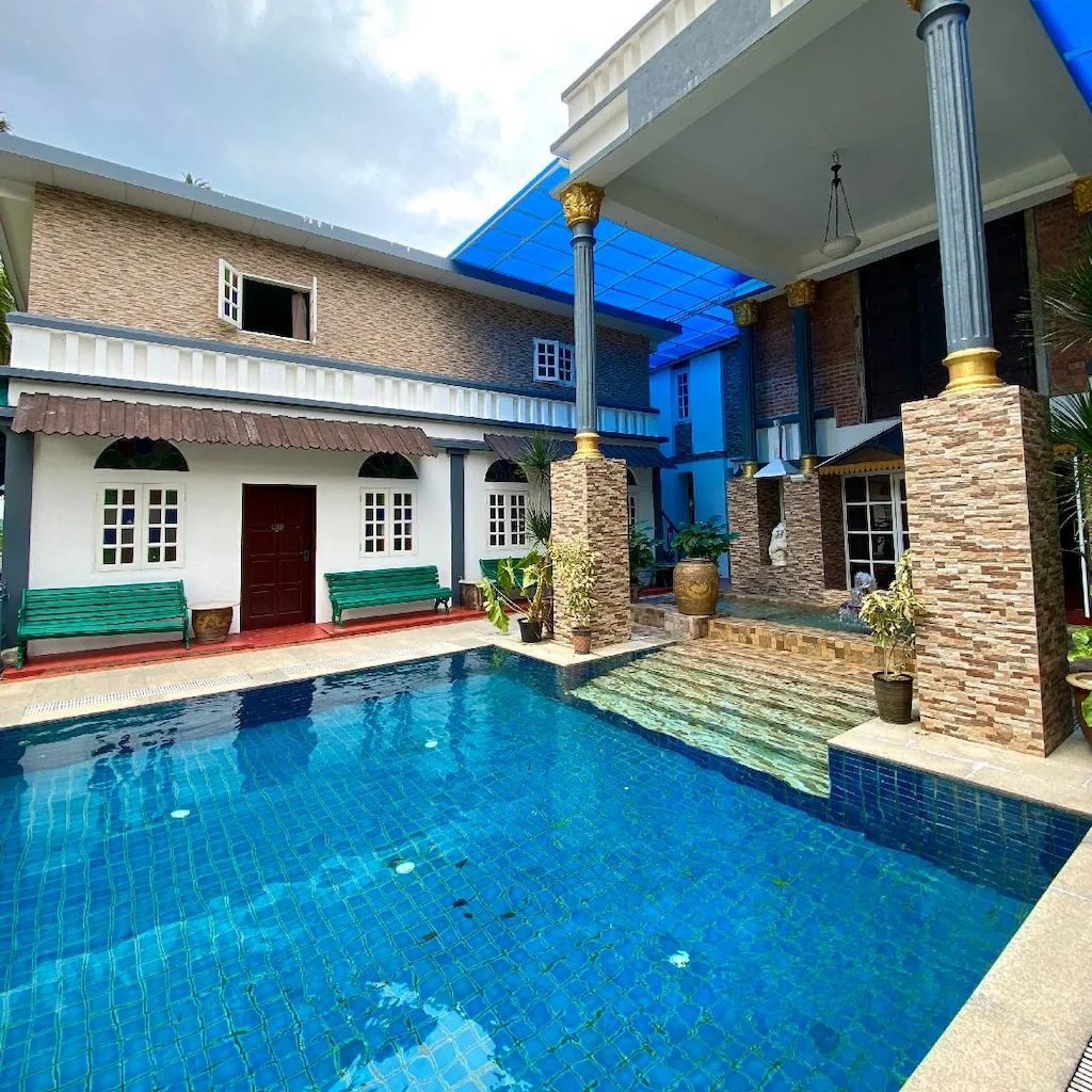 Outdoor pool at Bayu Bayu Hotel by Soft Loft, surrounded by a couple of green benches..