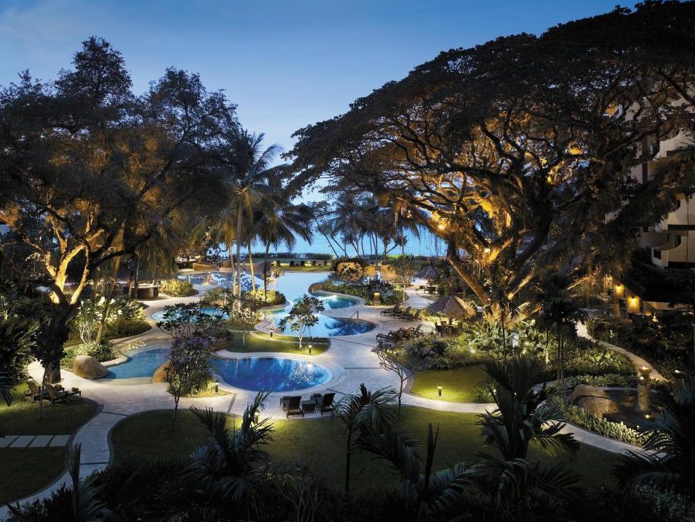 Rooftop‑style pool at Shangri‑La Rasa Sayang framed by towering rain trees, creating a lush, fairy‑tale atmosphere.