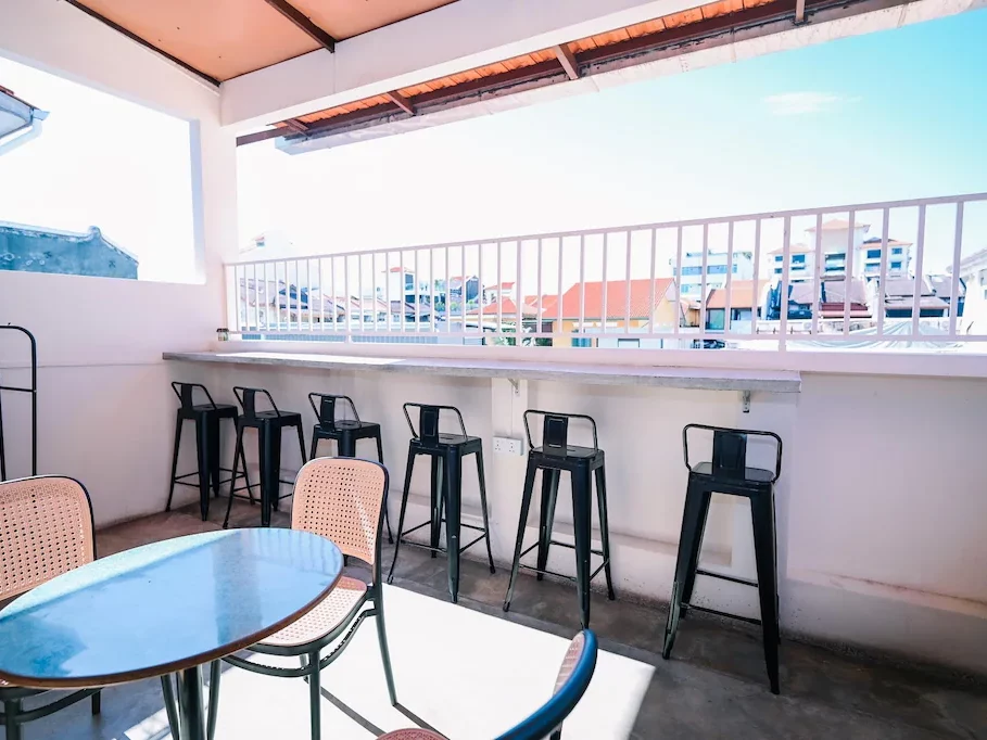 Rooftop area at Swing & Pillows featuring a round table with chairs, and high chairs facing a city view.