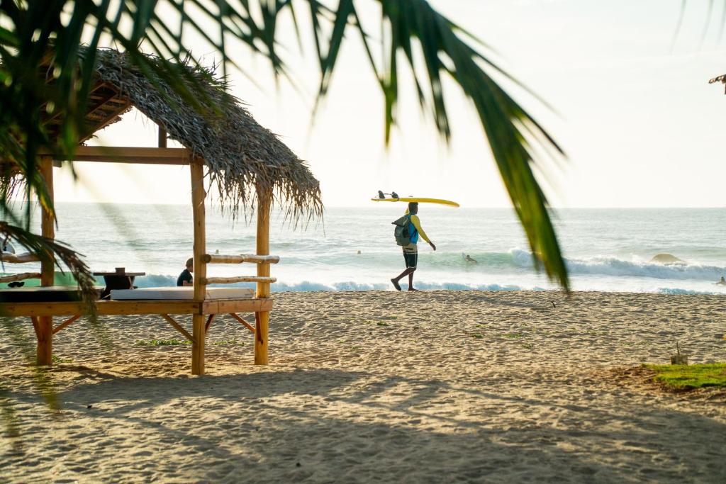 Man walking with a surfboard on top of his head at Whisky Point, Sri Lanka