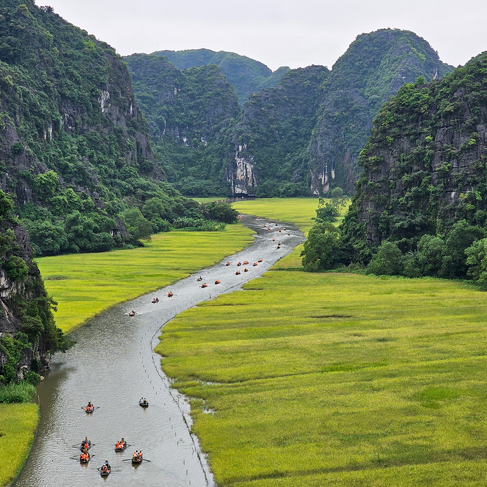Trang An boat tour in Ninh Binh, one of the highlights of this Vietnam 3‑week itinerary, showing rowboats moving through limestone cliffs and river valleys.