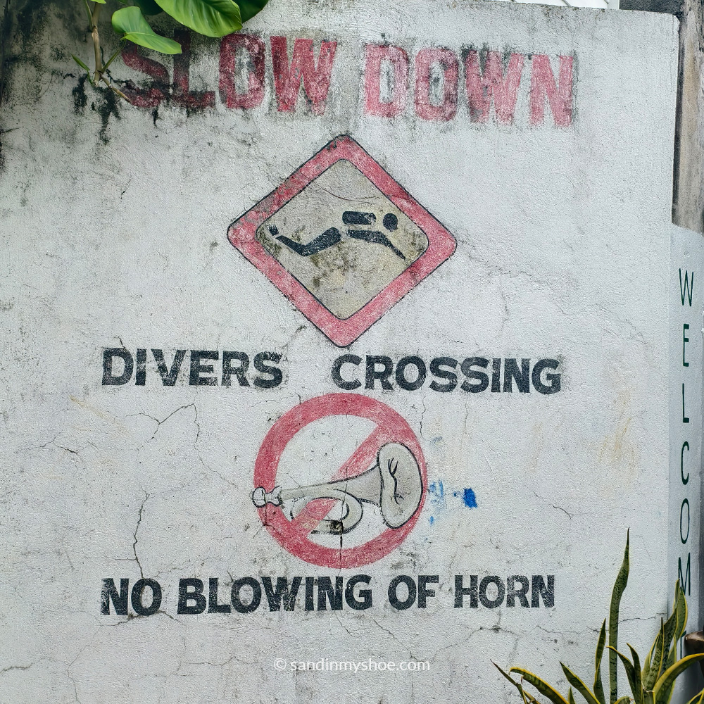 sign in malapscua that says slow down, divers crossing.