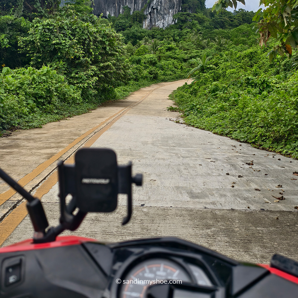 Petteri riding a motorbike on open road with jungle on both sides in Palawan, Philippines.