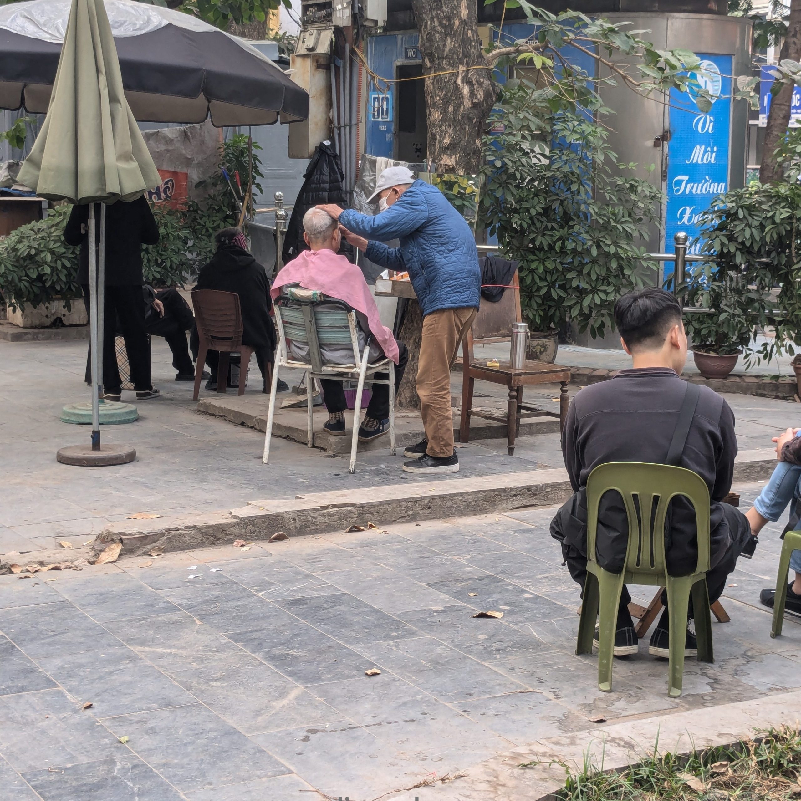 Man getting a haircut on the streets.