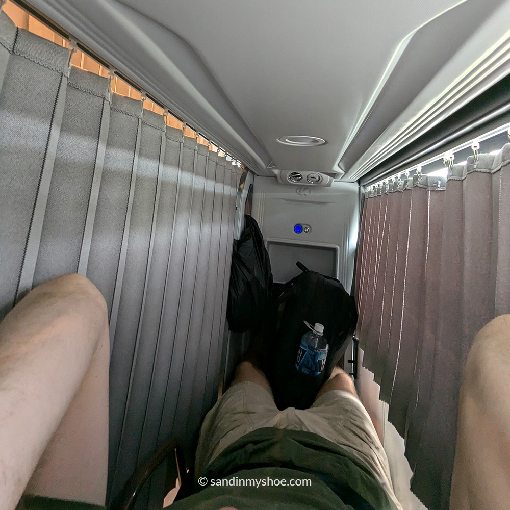 Petteri lying down in a sleeper bus with curtains closed.