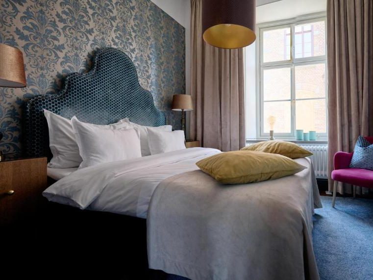 Cosy NOFO Hotel room with a comfortable bed and warm, home‑like décor.