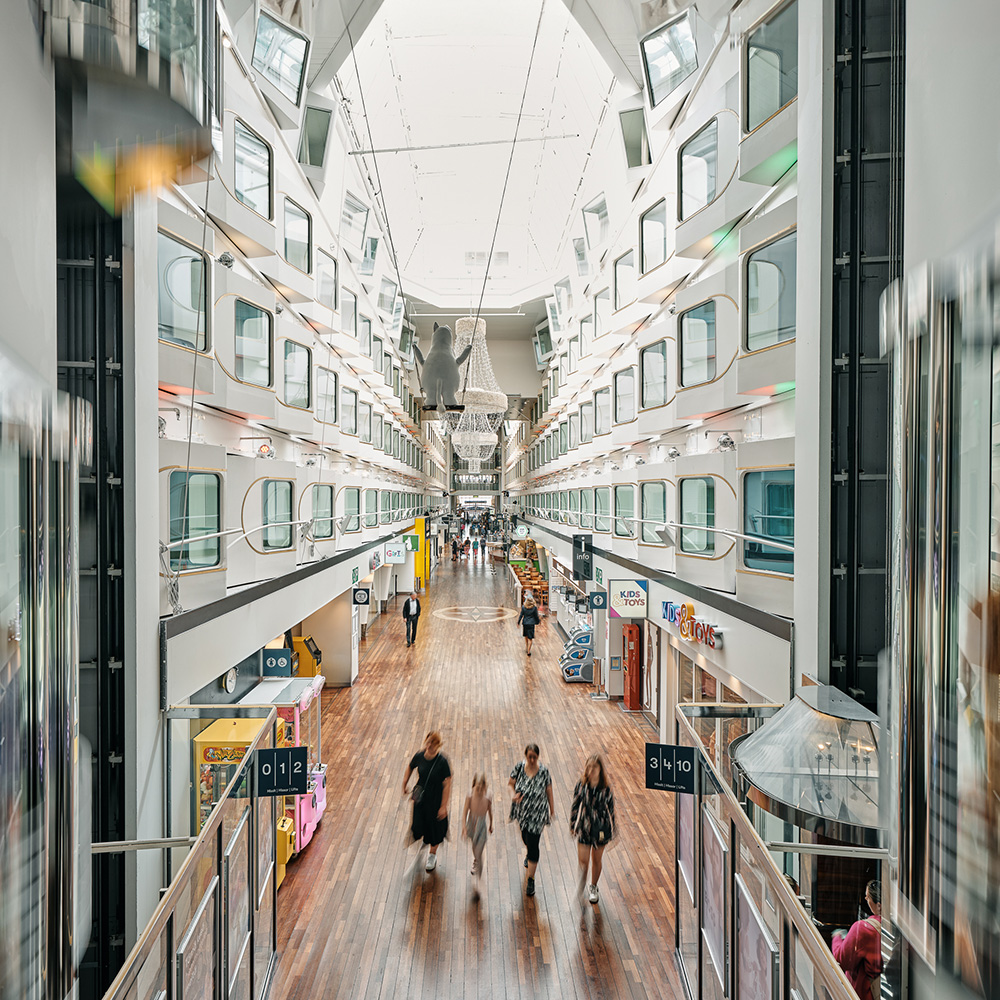 Interior view of Silja Symphony’s promenade, a long indoor street with shops, lights, and passengers walking through the heart of the ship.