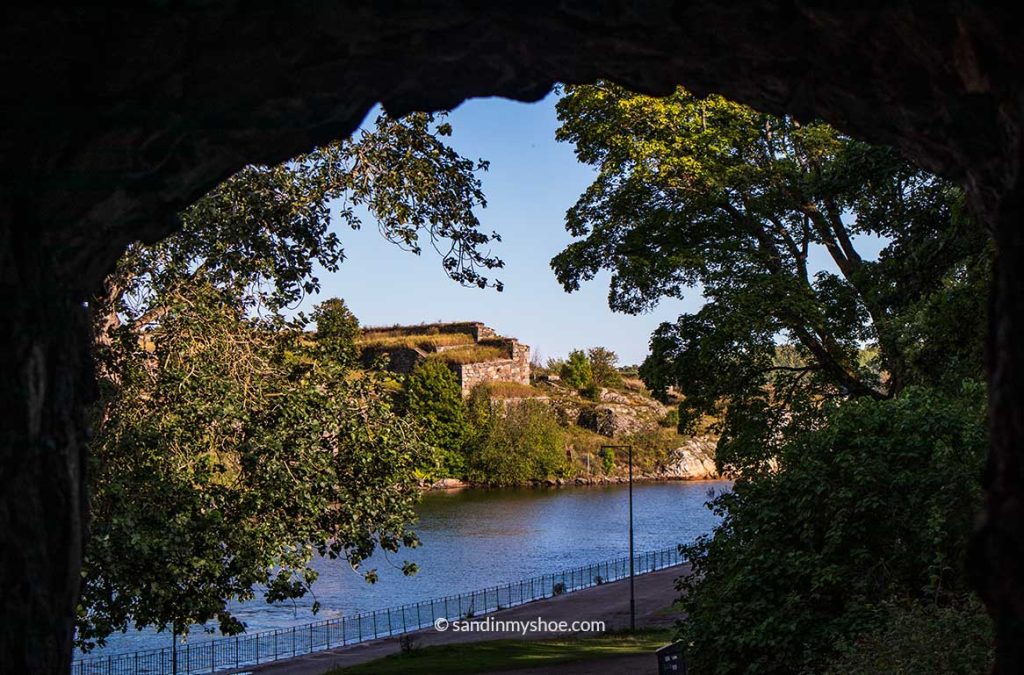 Stone wall at Suomenlinna Fortress beside the water, with rocky shoreline and calm sea highlighting the site's military history.