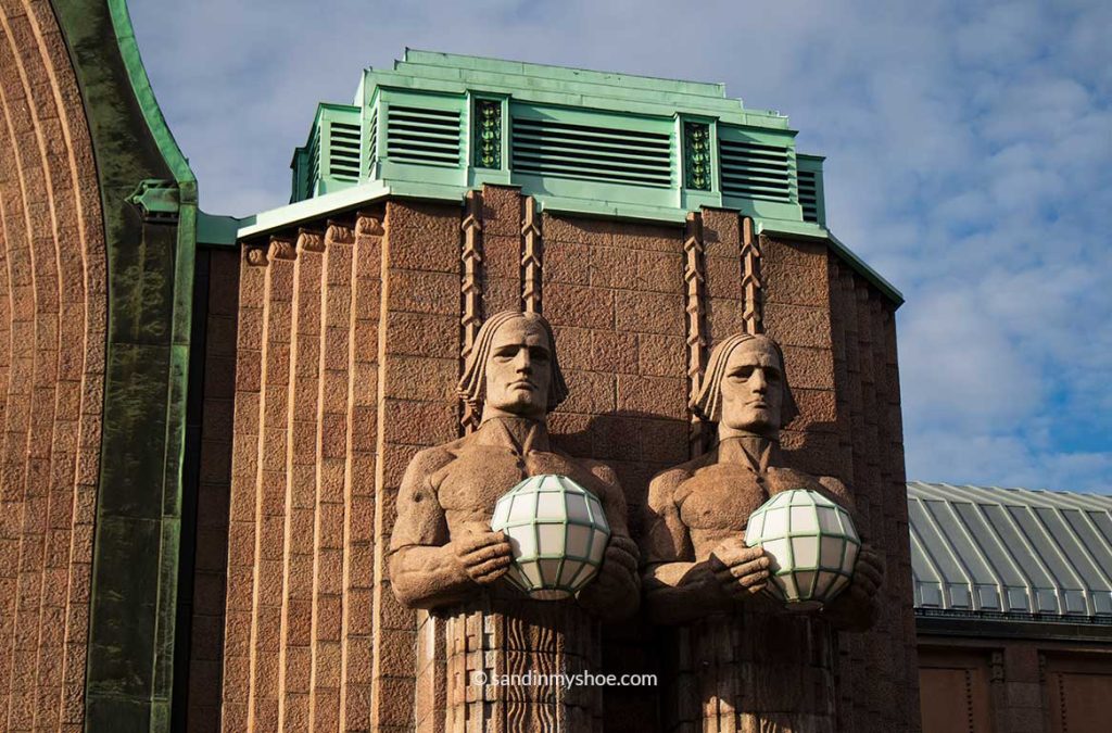 Two stones figures holding lanterns at central train station in Helsinki.